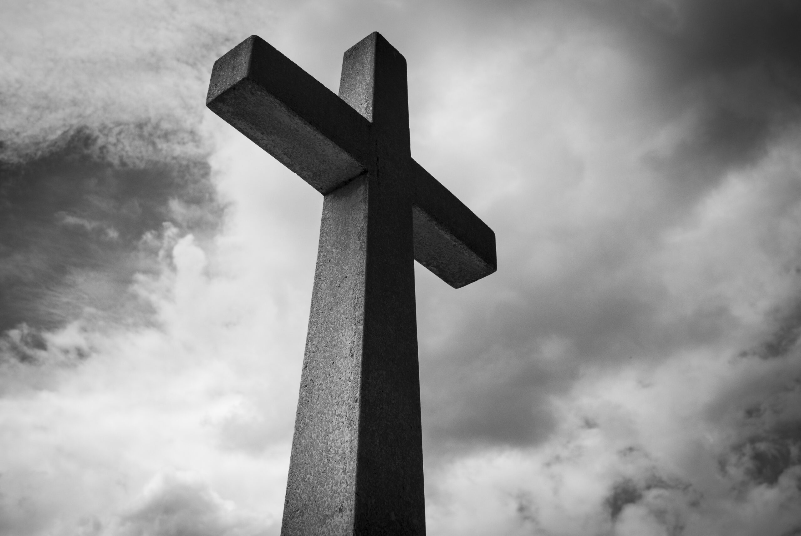 looking up at a cross with a cloudy background